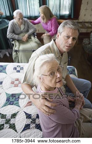 Picture - Adult children visiting and comforting senior parents in bedroom. Fotosearch