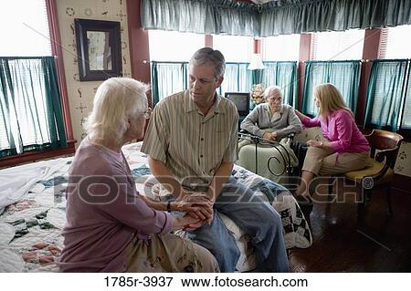 Adult children visiting and comforting senior parents in bedroom View Large Photo Image Stock Photo - Adult children visiting and comforting senior parents in bedroom. Fotosearch