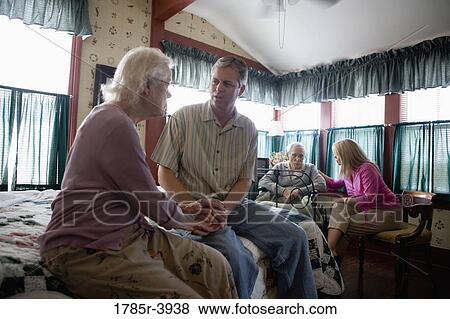 Stock Photo - Adult children visiting and comforting senior parents in bedroom. Fotosearch