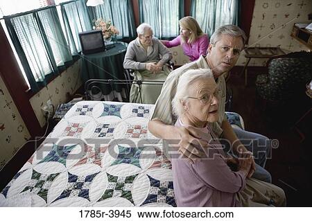 Stock Photography - Adult children visiting and comforting senior parents in bedroom. Fotosearch