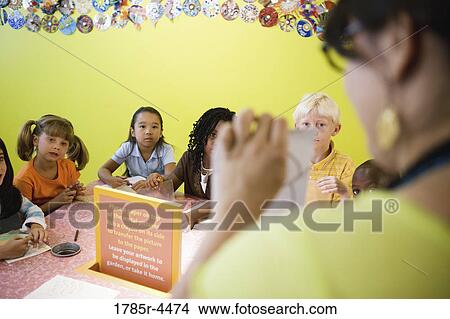 An art teacher demonstrating an art project to her young students in art class View Large Photo Image Picture - An art teacher demonstrating an art project to her young students in art class. Fotosearch