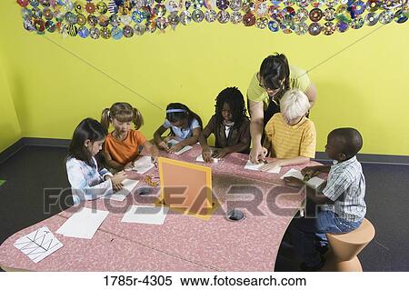 Stock Photography - An art teacher observing her students drawing in art class. Fotosearch