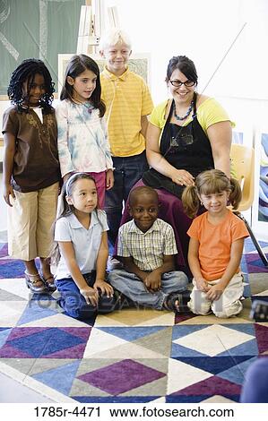Stock Image - An art teacher posing with her students in classroom. Fotosearch