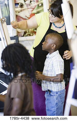 An art teacher showing her students how to draw on easels in art class View Large Photo Image Stock Photo - An art teacher showing her students how to draw on easels in art class. Fotosearch
