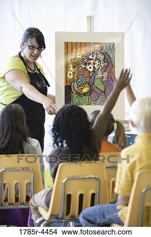 An art teacher showing painting to young students in art class View Large Photo Image Picture - An art teacher showing painting to young students in art class. Fotosearch