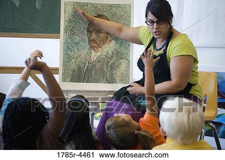Stock Image - An art teacher showing painting to young students in art class. Fotosearch