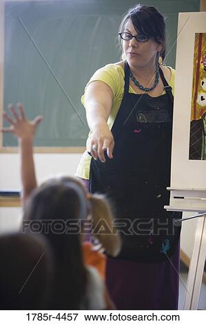 An art teacher showing painting to young students in art class View Large Photo Image Stock Photo - An art teacher showing painting to young students in art class. Fotosearch