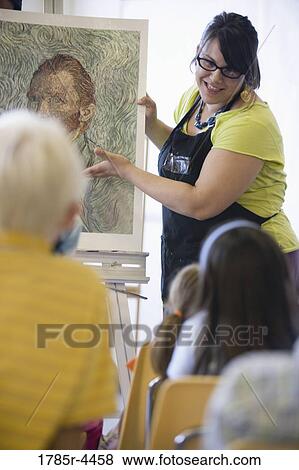 An art teacher showing painting to young students in art class View Large Photo Image Stock Photo - An art teacher showing painting to young students in art class. Fotosearch