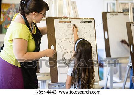 An art teacher showing young girl how to draw on an easel in art class View Large Photo Image Stock Image - An art teacher showing young girl how to draw on an easel in art class. Fotosearch