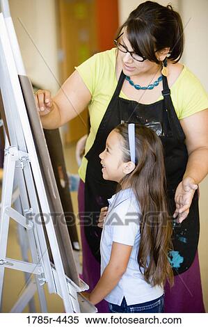 An art teacher showing young girl how to draw on an easel in art class View Large Photo Image Stock Photography - An art teacher showing young girl how to draw on an easel in art class. Fotosearch