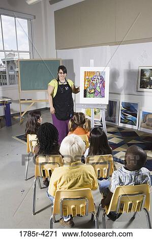 An art teacher standing by easel teaching her young students in art class View Large Photo Image Stock Image - An art teacher standing by easel teaching her young students in art class. Fotosearch