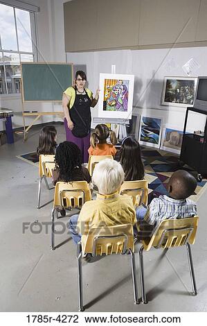 An art teacher standing by easel teaching her young students in art class View Large Photo Image Stock Image - An art teacher standing by easel teaching her young students in art class. Fotosearch
