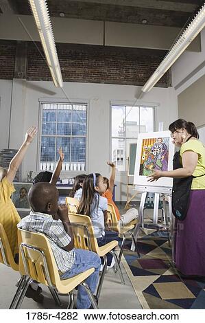 An art teacher standing by easel teaching her young students in art class View Large Photo Image Stock Image - An art teacher standing by easel teaching her young students in art class. Fotosearch
