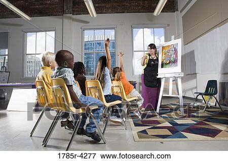An art teacher standing by easel teaching her young students in art class View Large Photo Image Stock Photo - An art teacher standing by easel teaching her young students in art class. Fotosearch