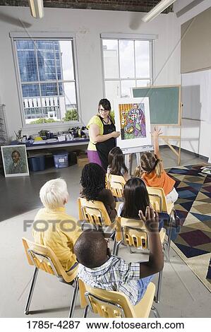 An art teacher standing by easel teaching her young students in art class View Large Photo Image Stock Photo - An art teacher standing by easel teaching her young students in art class. Fotosearch