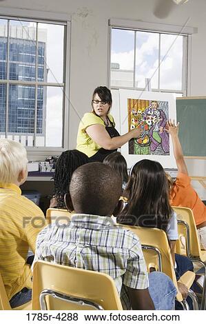 An art teacher standing by easel teaching her young students in art class View Large Photo Image Stock Photo - An art teacher standing by easel teaching her young students in art class. Fotosearch