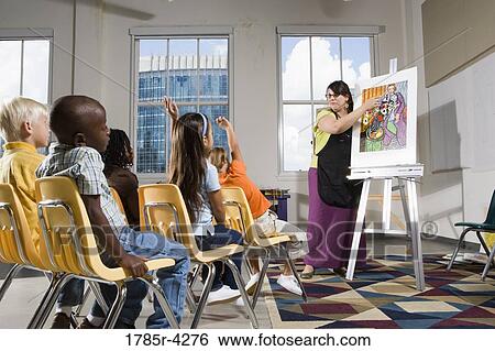 An art teacher standing by easel teaching her young students in art class View Large Photo Image Stock Photograph - An art teacher standing by easel teaching her young students in art class. Fotosearch