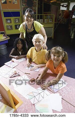 Stock Image - An art teacher teaching her young students in art class. Fotosearch