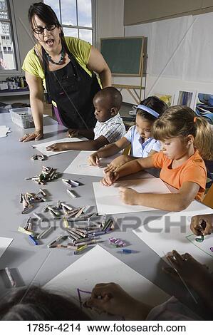 An art teacher teaching young students in art class View Large Photo Image Picture - An art teacher teaching young students in art class. Fotosearch
