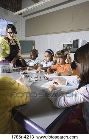 Stock Image - An art teacher teaching young students in art class. Fotosearch