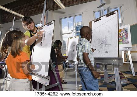 An art teacher with her student drawing on easels in art class View Large Photo Image Stock Image - An art teacher with her student drawing on easels in art class. Fotosearch