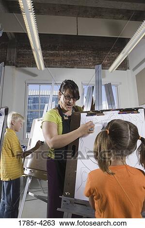 An art teacher with her student drawing on easels in art class View Large Photo Image Stock Image - An art teacher with her student drawing on easels in art class. Fotosearch