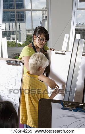 An art teacher with her student drawing on easels in art class View Large Photo Image Stock Photography - An art teacher with her student drawing on easels in art class. Fotosearch