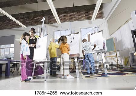 An art teacher with her student drawing on easels in art class View Large Photo Image Stock Photography - An art teacher with her student drawing on easels in art class. Fotosearch