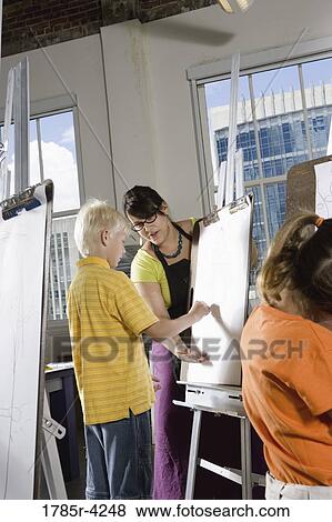 An art teacher with her students drawing on easels in art class View Large Photo Image Stock Photo - An art teacher with her students drawing on easels in art class. Fotosearch