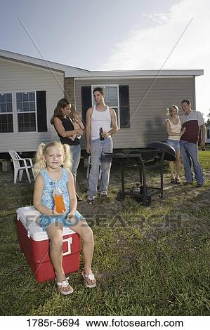 Picture - Blue collar families enjoying a cookout in front of trailer home. Fotosearch