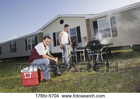 Blue collar families enjoying a cookout in front of trailer home View Large Photo Image Picture - Blue collar families enjoying a cookout in front of trailer home. Fotosearch