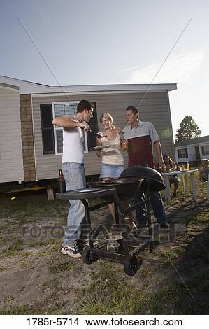 Blue collar families enjoying a cookout in front of trailer home View Large Photo Image Picture - Blue collar families enjoying a cookout in front of trailer home. Fotosearch