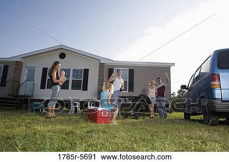 Stock Image - Blue collar families enjoying a cookout in front of trailer home. Fotosearch