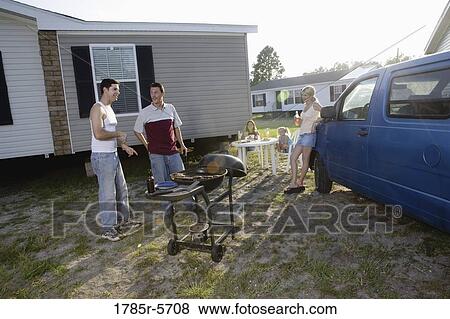 Blue collar families enjoying a cookout in front of trailer home View Large Photo Image Stock Photo - Blue collar families enjoying a cookout in front of trailer home. Fotosearch