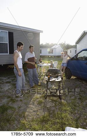 Blue collar families enjoying a cookout in front of trailer home View Large Photo Image Stock Photo - Blue collar families enjoying a cookout in front of trailer home. Fotosearch