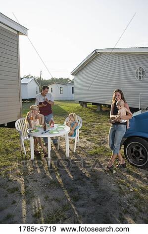 Blue collar families enjoying a cookout in front of trailer home View Large Photo Image Stock Photo - Blue collar families enjoying a cookout in front of trailer home. Fotosearch