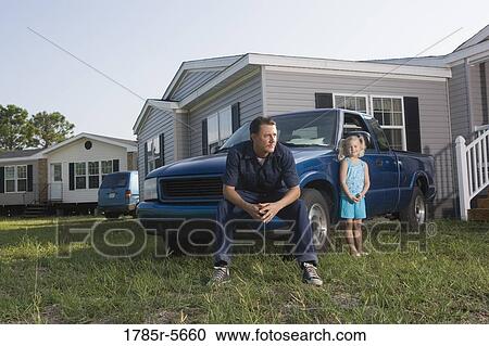 Blue-collar man sitting on old truck in front of trailer home with daughter View Large Photo Image Stock Image - Blue-collar man sitting on old truck in front of trailer home with daughter. Fotosearch