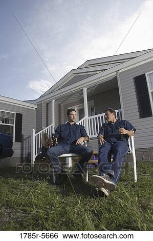 Blue-collar men sitting and holding drink bottles in front yard of trailer home View Large Photo Image Stock Photograph - Blue-collar men sitting and holding drink bottles in front yard of trailer home. Fotosearch