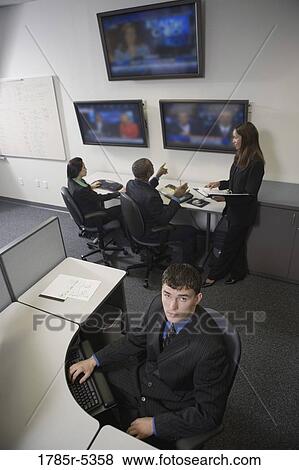 Bored office worker at his desk with co-workers in the background View Large Photo Image Stock Photo - Bored office worker at his desk with co-workers in the background. Fotosearch