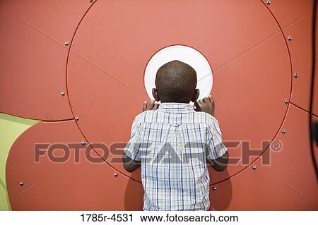 Boy (5-6) looking through opening in a colorful wall View Large Photo Image Stock Image - Boy (5-6) looking through opening in a colorful wall. Fotosearch