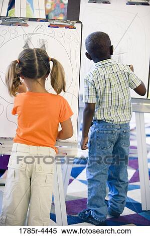 Boy and girl drawing on easels in art class View Large Photo Image Stock Photography - Boy and girl drawing on easels in art class. Fotosearch