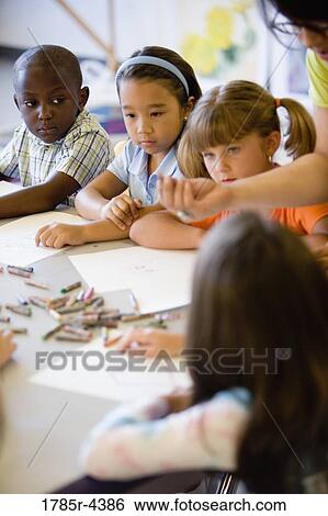 Boy and girls paying attention to teacher in an art class View Large Photo Image Stock Photograph - Boy and girls paying attention to teacher in an art class. Fotosearch