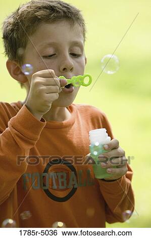 Stock Photograph - Boy blowing bubbles at a park. Fotosearch