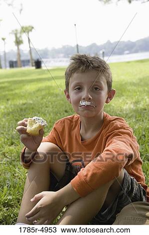 Boy eating a cupcake at a park View Large Photo Image Stock Image - Boy eating a cupcake at a park. Fotosearch