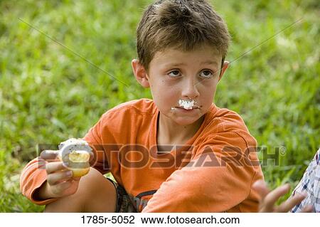Boy eating a cupcake at a park View Large Photo Image Stock Image - Boy eating a cupcake at a park. Fotosearch