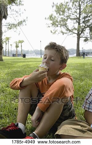 Boy eating a cupcake at a park View Large Photo Image Stock Photo - Boy eating a cupcake at a park. Fotosearch
