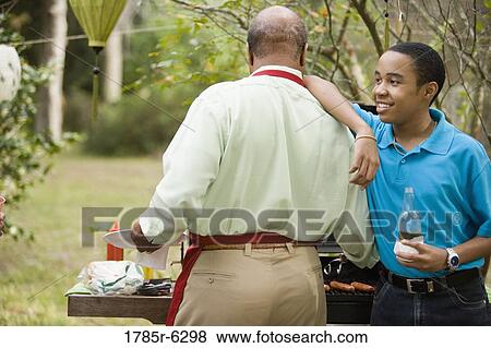 Boy leaning on his father's shoulder at bbq grill View Large Photo Image Stock Photo - Boy leaning on his father's shoulder at bbq grill. Fotosearch