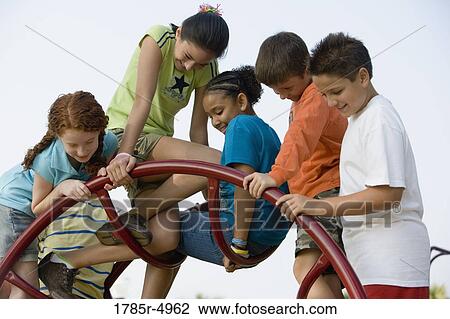 Stock Image - Boys and girls climbing on monkey bars at a playground. Fotosearch