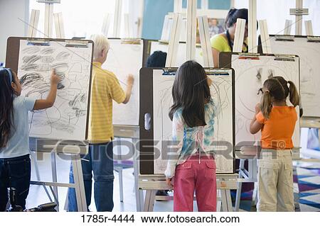 Boys and girls drawing on easels in art class View Large Photo Image Picture - Boys and girls drawing on easels in art class. Fotosearch