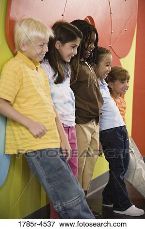 Stock Photo - Boys and girls posing and leaning against a colorful wall. Fotosearch